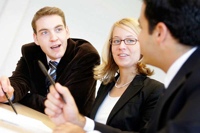 3 Studierende nebeneinander am Tisch im Gespräch